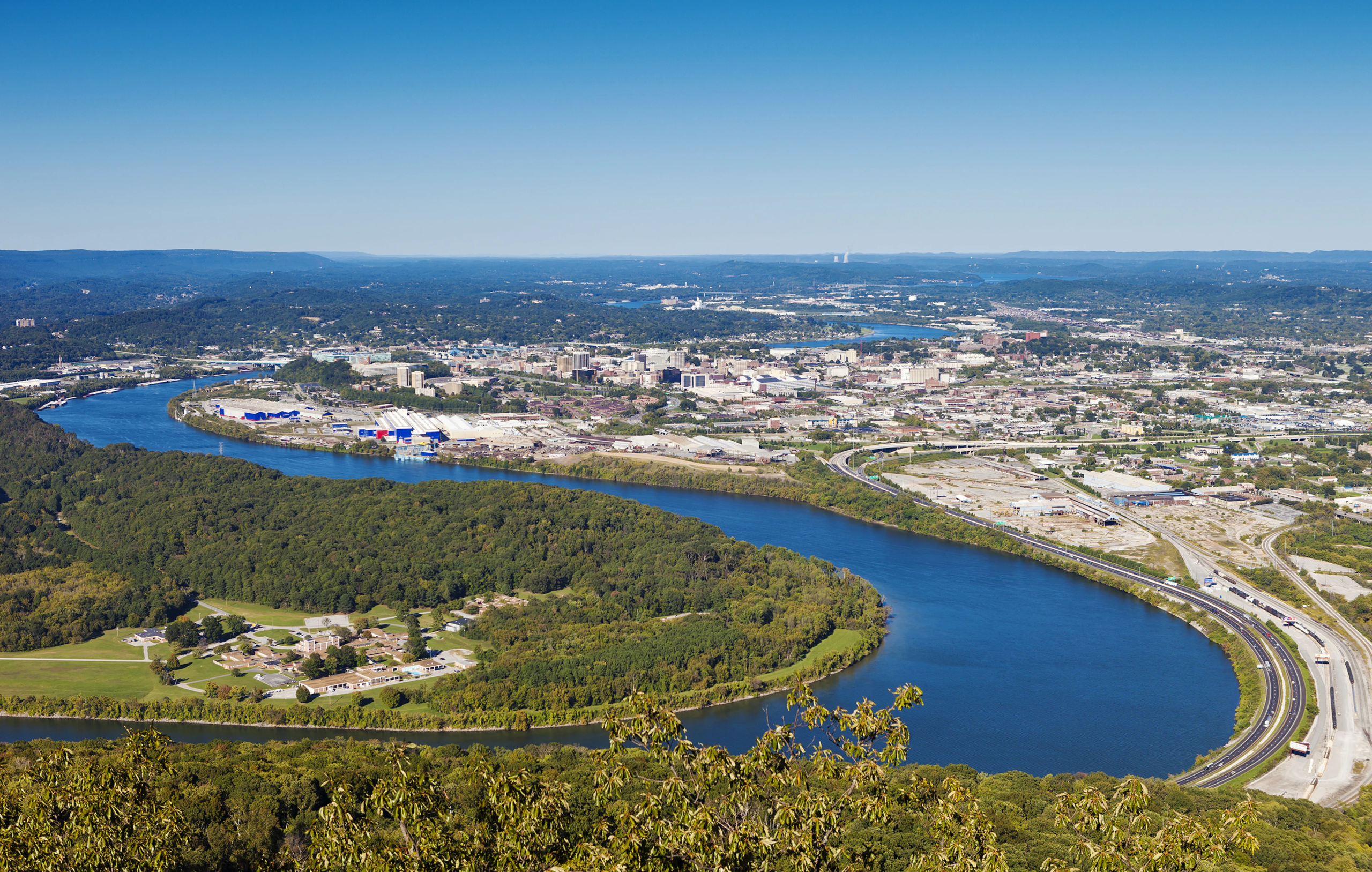 Aerial view of Chattanooga, Tennessee, with the Tennessee River, downtown buildings, and surrounding mountains.